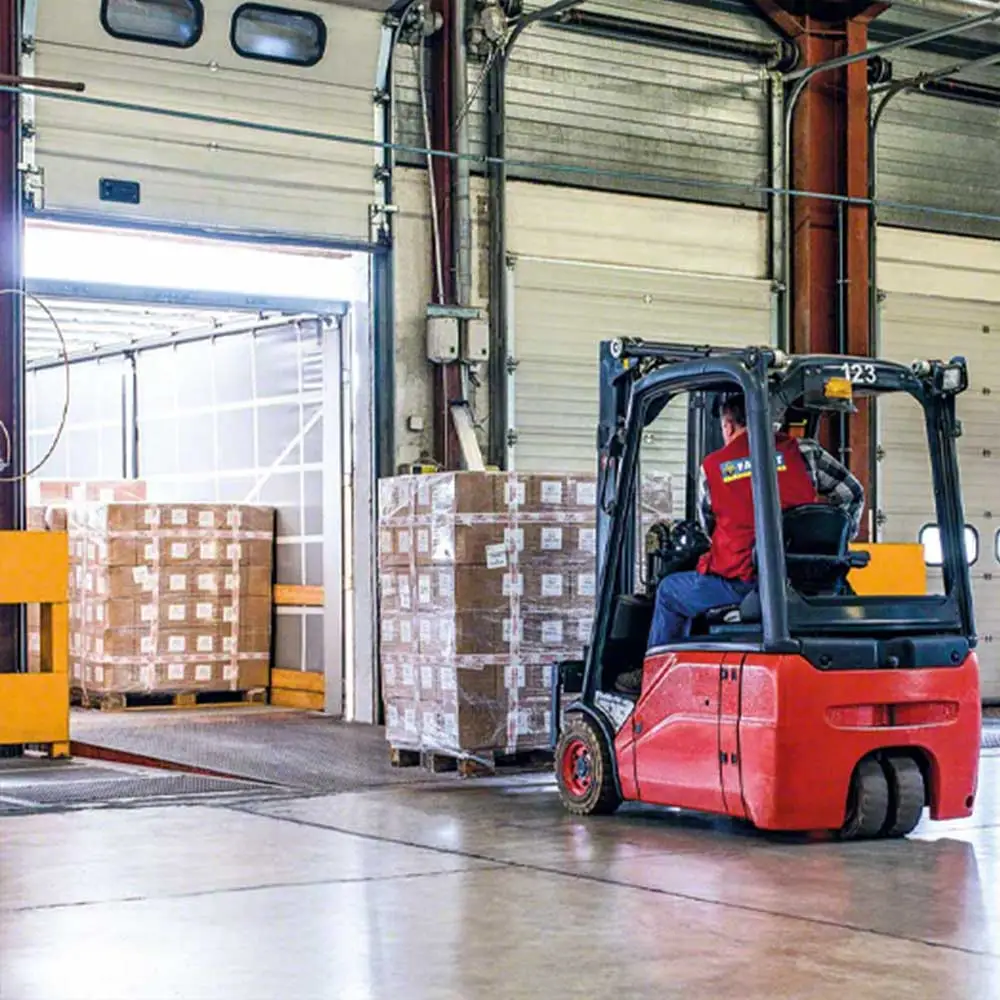 Worker operating a forklift to load pallets of goods inside a warehouse, demonstrating efficient material handling